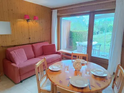 a living room with a table and a red couch at Les hautes Cimes in Saint-Gervais-les-Bains