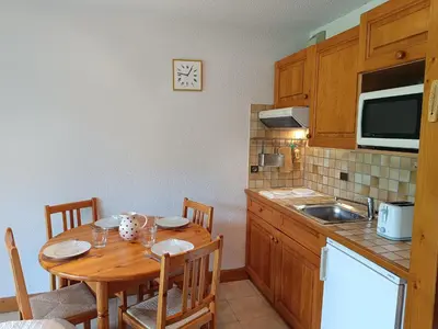 a kitchen with a wooden table with chairs and a sink at Les hautes Cimes in Saint-Gervais-les-Bains