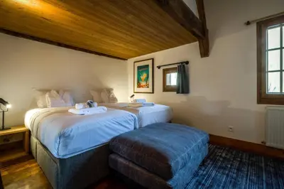 a hotel room with two beds and a ottoman at Rosaline Ferme 220m2 Charme Cheminee Jacuzzi Sauna in Les Houches