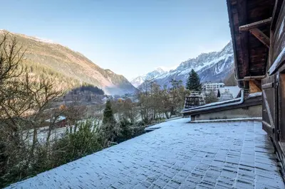 a stone walkway next to a building with mountains in the background at Rosaline Ferme 220m2 Charme Cheminee Jacuzzi Sauna in Les Houches