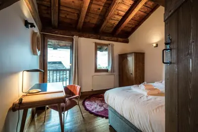 a bedroom with a bed and a desk and a window at Rosaline Ferme 220m2 Charme Cheminee Jacuzzi Sauna in Les Houches