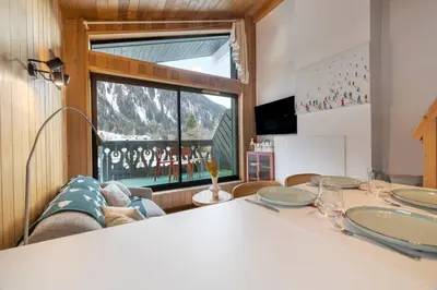 a living room with a table and a large window at Petit Montana Apart 2CH Vues Garage 5mn Grands Montets in Chamonix-Mont-Blanc