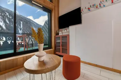 a living room with a vase and a table and a window at Petit Montana Apart 2CH Vues Garage 5mn Grands Montets in Chamonix-Mont-Blanc