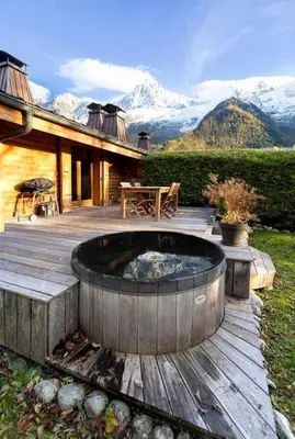 a wooden deck with a fire pit in front of a house at Momi Cocon 4pax Jardin Jacuzzi Vue in Chamonix-Mont-Blanc