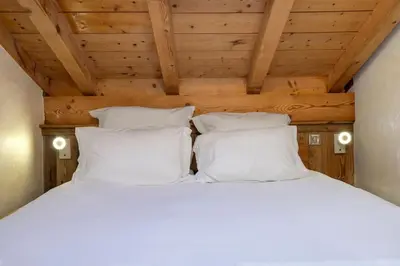 a bed with white pillows in a wooden ceiling at Momi Cocon 4pax Jardin Jacuzzi Vue in Chamonix-Mont-Blanc