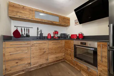 a kitchen with wooden cabinets and red appliances at Momi Cocon 4pax Jardin Jacuzzi Vue in Chamonix-Mont-Blanc