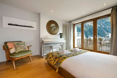 a bedroom with a bed and a chair and a fireplace at Guérin Cosy 4pax Familial Vue Central in Chamonix-Mont-Blanc