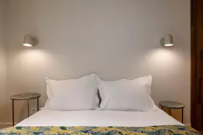 a bed with white sheets and pillows and two tables at Guérin Cosy 4pax Familial Vue Central in Chamonix-Mont-Blanc