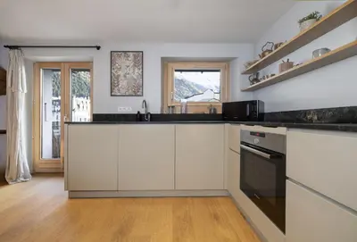 a kitchen with white cabinets and black counter tops at Guérin Cosy 4pax Familial Vue Central in Chamonix-Mont-Blanc