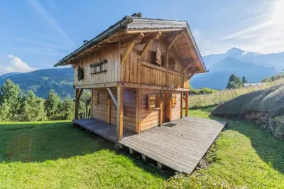 a small wooden house with a deck in a field at Lays Mazot Calme Vues Parking in Saint-Gervais-les-Bains
