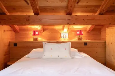 a bed in a wooden cabin with two lights on it at Lays Mazot Calme Vues Parking in Saint-Gervais-les-Bains