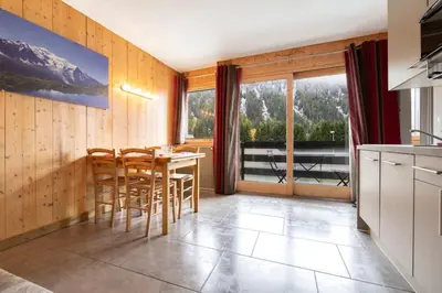 a kitchen with a table and chairs and a large window at Posette Studio Vue 5mn Pistes Parking in Chamonix-Mont-Blanc