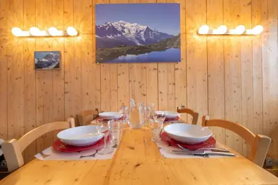 a dining room with a wooden table with wine glasses at Posette Studio Vue 5mn Pistes Parking in Chamonix-Mont-Blanc