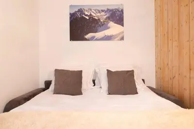 a bedroom with a bed with white sheets and brown pillows at Posette Studio Vue 5mn Pistes Parking in Chamonix-Mont-Blanc