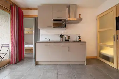 a kitchen with white cabinets and an open door at Posette Studio Vue 5mn Pistes Parking in Chamonix-Mont-Blanc