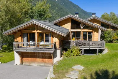 a large wooden house with a large deck and mountains at Vieil Ours Douillet Chalet 11pax Familial Vue in Chamonix-Mont-Blanc