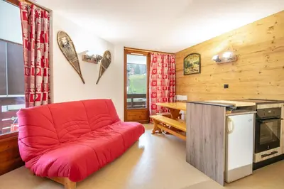 a red couch in a living room with a kitchen at Le Repos du Skieur - Au pied des pistes in Morillon