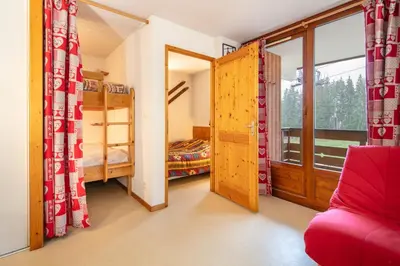 a bedroom with a bunk bed and a red couch at Le Repos du Skieur - Au pied des pistes in Morillon