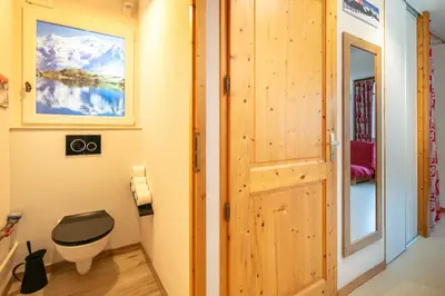 a bathroom with a toilet and a wooden door at Le Repos du Skieur - Au pied des pistes in Morillon