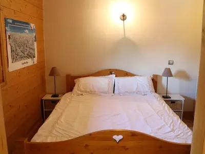 a bedroom with a wooden bed with white sheets and pillows at Charmant duplex 7 pers à Samoëns avec piscine et Wi-Fi - FR-1-815-46 in Samoëns