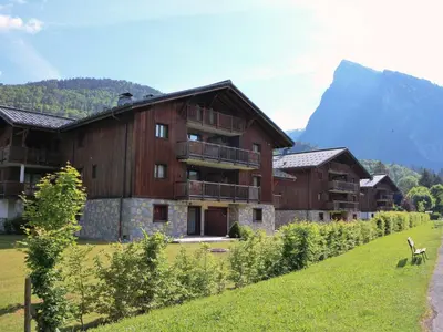 a large wooden building with a mountain in the background at Charmant duplex 7 pers à Samoëns avec piscine et Wi-Fi - FR-1-815-46 in Samoëns