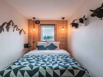 a bedroom with a bed with blue pillows and a window at Duplex au pied de la télécabine à Megève - 4 chambres - FR-1-569-204 in Megève