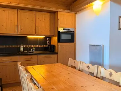 a kitchen with a wooden table with chairs and a kitchen gmaxwell gmaxwell gmaxwell at Appartement cosy 3 pièces près des pistes avec parking - FR-1-572-344 in Arâches-la-Frasse