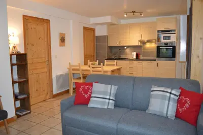 a living room with a blue couch and a kitchen at Appartement aux portes de St Gervais in Saint-Gervais-les-Bains