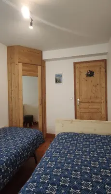 a bedroom with two beds and a wooden door at Appartement aux portes de St Gervais in Saint-Gervais-les-Bains