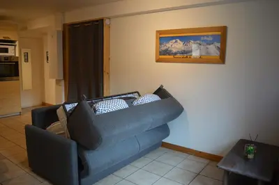 a living room with a blue couch and a picture on the wall at Appartement aux portes de St Gervais in Saint-Gervais-les-Bains