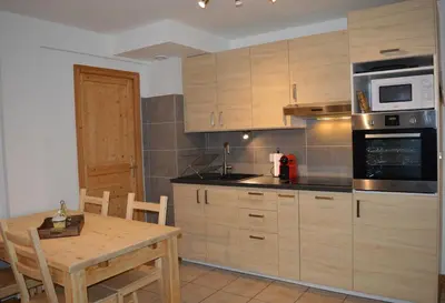 a kitchen with wooden cabinets and a table and a microwave at Appartement aux portes de St Gervais in Saint-Gervais-les-Bains