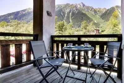 a table and chairs on a balcony with mountains at Grand Paradis B11 - Good location & parking in Chamonix-Mont-Blanc