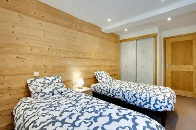 two beds in a room with wooden walls at Grand Paradis B11 - Good location & parking in Chamonix-Mont-Blanc
