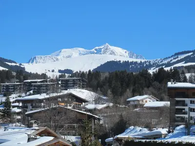 a town with snow covered mountains in the background at Megève 105 m2 ensoleillé rénové au pied des pistes in Megève