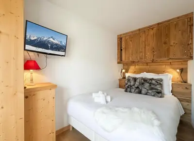 a bedroom with a bed with a tv on the wall at Melba Megeve emplacement de rêve dans le village au calme in Megève