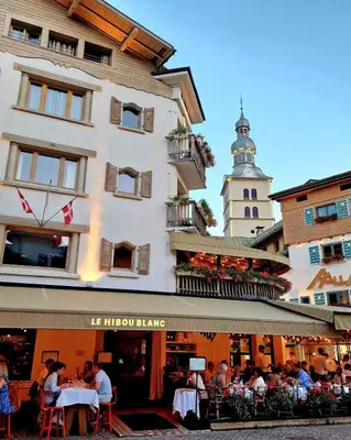 a group of people sitting at tables in front of a building at Melba Megeve emplacement de rêve dans le village au calme in Megève