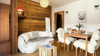 a living room with white furniture and a wooden wall at Melba Megeve emplacement de rêve dans le village au calme in Megève