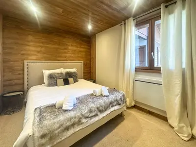 a bedroom with a bed and a wooden wall at Sapins blancs Megeve in Megève