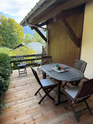 a patio with a table and chairs on a wooden deck at Sapins blancs Megeve in Megève