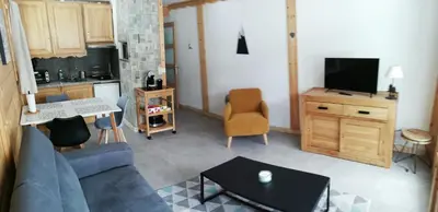 a living room with a blue couch and a tv at Apparement cosy 4 personnes in Samoëns