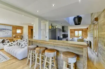a kitchen and living room with a couch and stools at Bright chalet in Combloux close to the slopes in Combloux