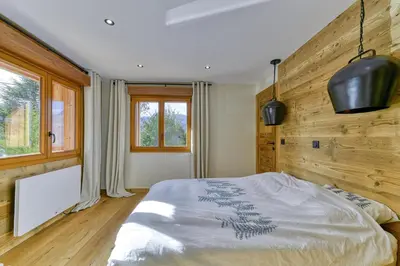 a bedroom with a bed and a wooden wall at Bright chalet in Combloux close to the slopes in Combloux