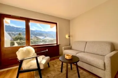 a living room with a couch and a large window at Bright apartment with terrace in Megève in Megève