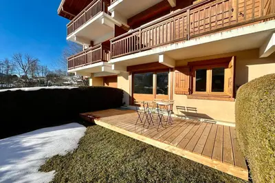 a house with a wooden deck with chairs on it at Bright apartment with terrace in Megève in Megève