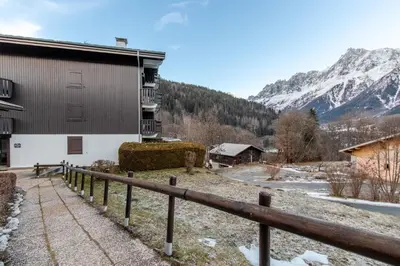 a building with a fence in front of a mountain at Le Cocon du Prarion in Les Houches