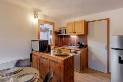 a small kitchen with a table and a refrigerator at Le Cocon du Prarion in Les Houches