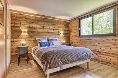 a bedroom with wooden walls and a bed with blue pillows at Chalet 18 guests, 8 bedrooms, 5 bathrooms & Sauna! in Les Houches