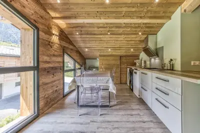 a kitchen with wooden walls and a table with chairs at Chalet 18 guests, 8 bedrooms, 5 bathrooms & Sauna! in Les Houches