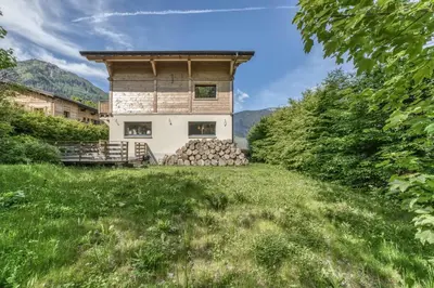 a house with a pile of logs in a field at Chalet 18 guests, 8 bedrooms, 5 bathrooms & Sauna! in Les Houches