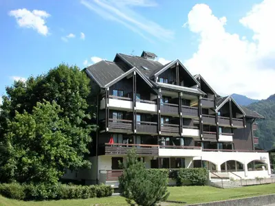 a large building on a hill with mountains in the background at Studio cosy au centre de Samoëns pour 4 pers, animaux admis - FR-1-629-153 in Samoëns